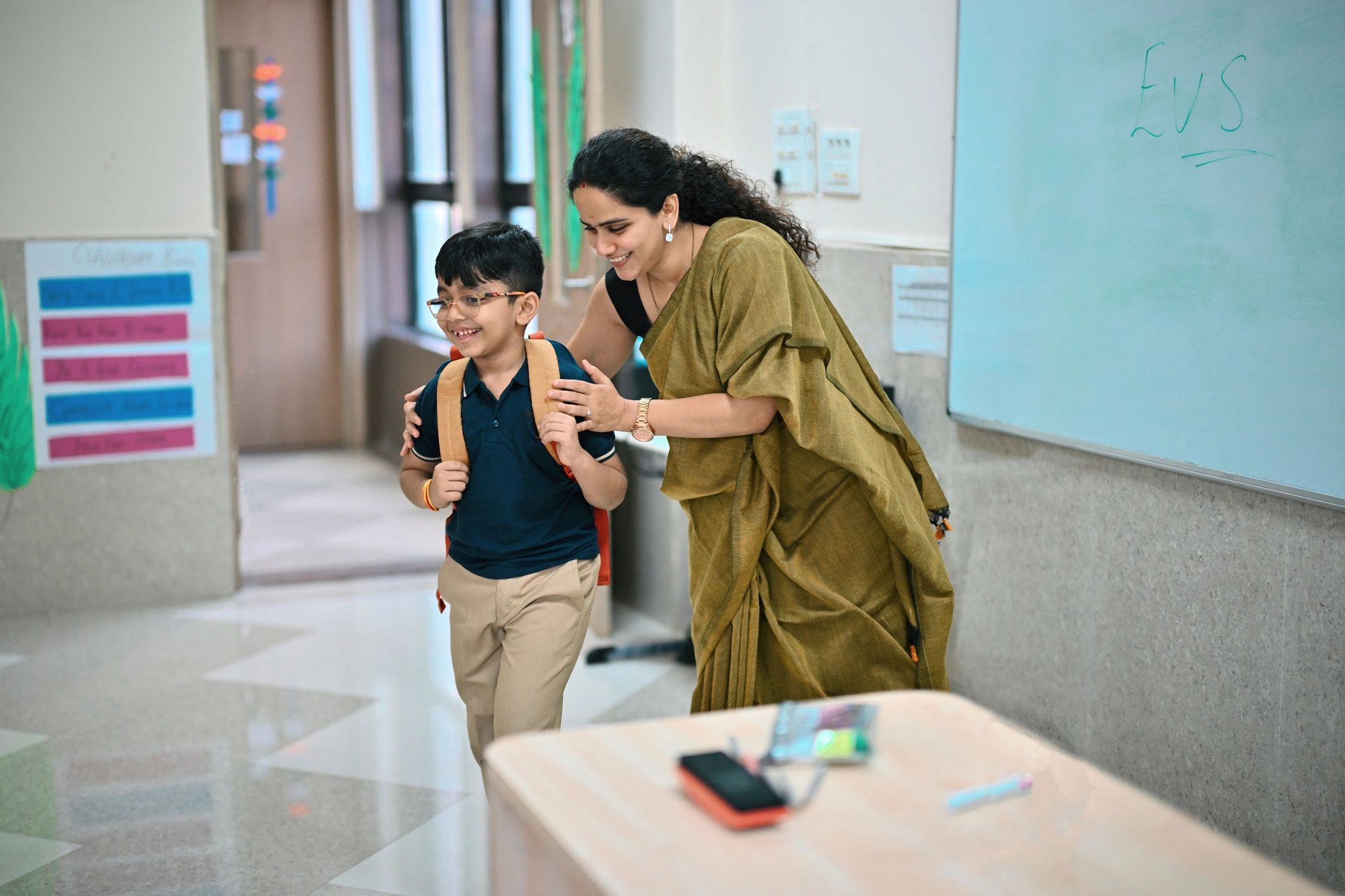Teacher warmly guiding a student in a classroom supported by community programs